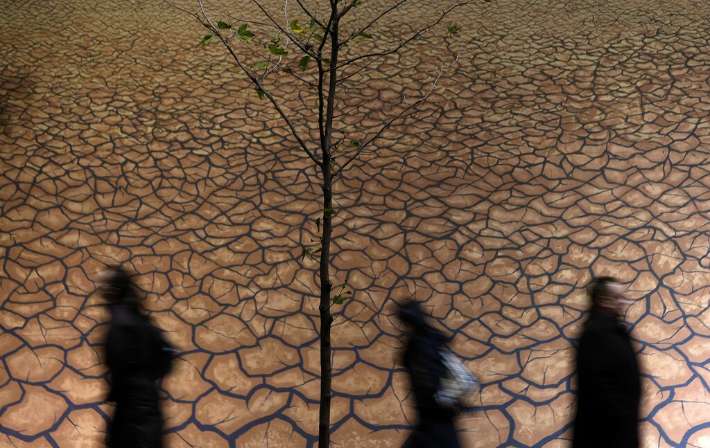 Office workers walk past a mural of a drought scene in the business district of Melbourne, 2008.