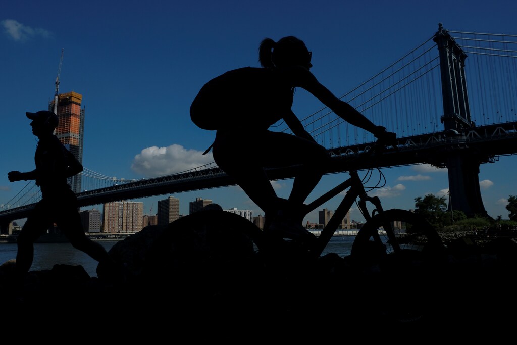 People jog and cycle near Manhattan Bridge in the Brooklyn borough of New York City, U.S., September 15, 2017. REUTERS/Darrin Zammit Lupi - RC1A7AF7EEB0