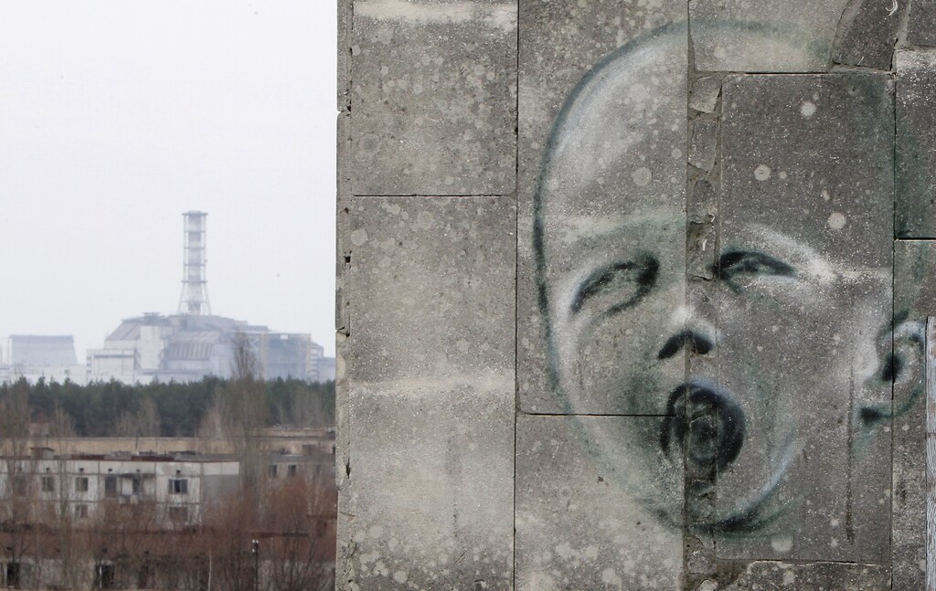 The sarcophagus covering the damaged fourth reactor at the Chernobyl nuclear power plant is seen behind a building decorated with a graffiti in the abandoned city of Prypiat April 4, 2011. Belarus, Ukraine and Russia will mark the 25th anniversary of the nuclear reactor explosion in Chernobyl, the place where the world's worst civil nuclear accident took place, on April 26. Engineers are still struggling to regain control of damaged reactors at the Fuskushima plant after last month's earthquake and tsunami, in the worst nuclear crisis since Chernobyl in 1986, with the government urging the operator of the plant to act faster to stop radiation spreading. REUTERS/Gleb Garanich (UKRAINE - Tags: ANNIVERSARY DISASTER ENERGY ENVIRONMENT IMAGES OF THE DAY) - GM1E74500L501
