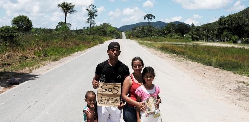 Venezuelan family from Aragua state pose for a picture as they attempt to hitchhike toward Boa Vista city, after they obtained refugee status or temporary residence, through the Federal Police and the United Nations High Commissioner for Refugees (UNHCR), at the Pacaraima border control, Roraima state, Brazil August 10, 2018.