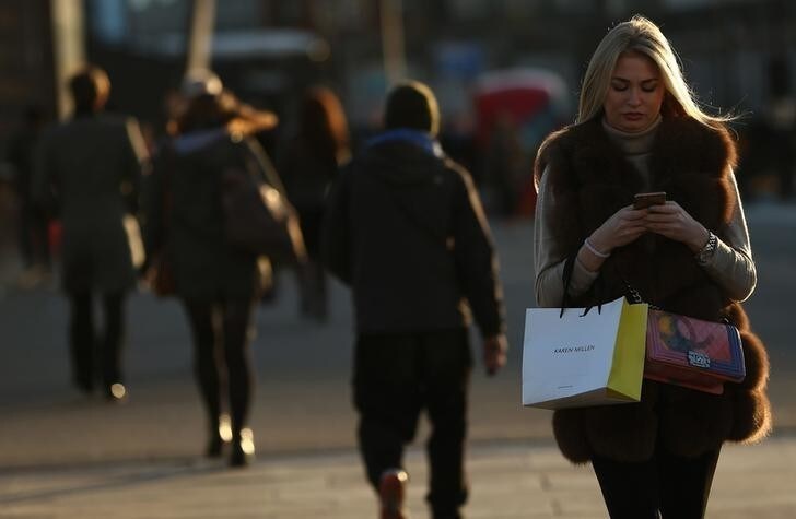 A woman checks her phone as she walks across London Bridge on the second day of a train strike in London, Britain December 14, 2016. REUTERS/Neil Hall