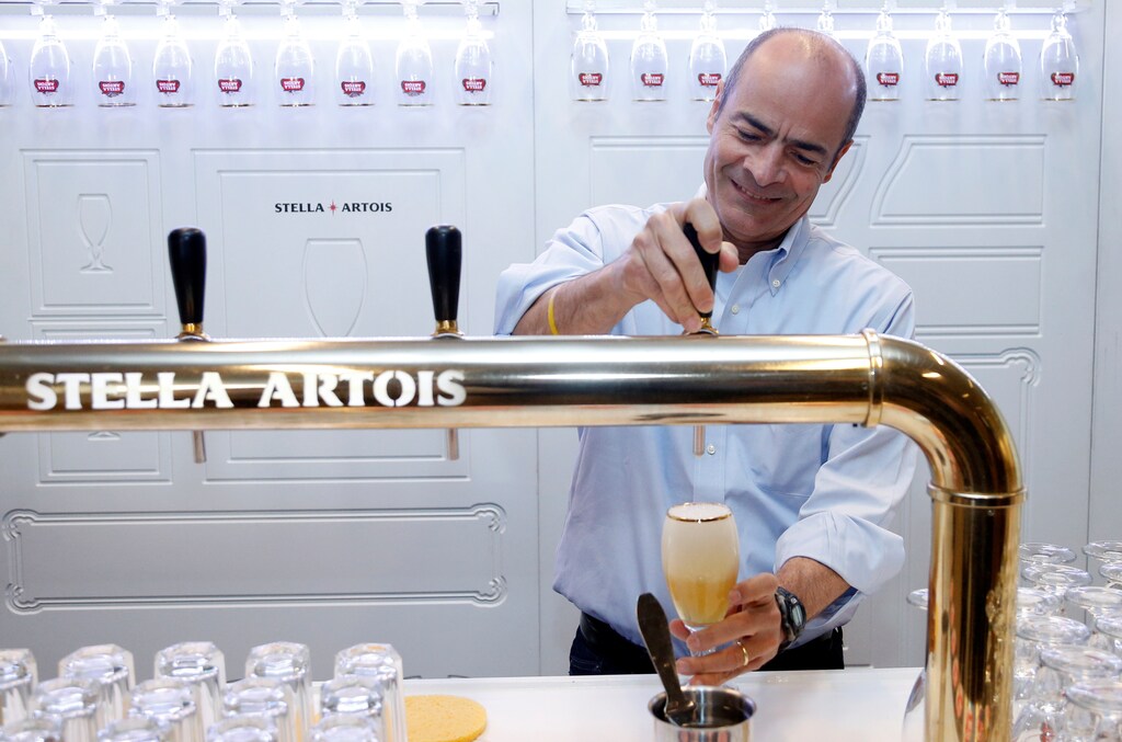 Carlos Brito, Chief Executive of Anheuser-Busch InBev, taps a Stella Artois beer after a news conference in Leuven, Belgium March 1, 2018.