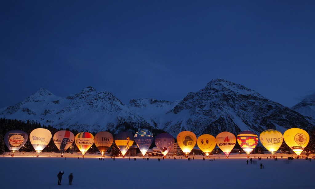 Spectators take pictures as hot air balloons are gathered on the frozen Upper Lake for the traditional glooming during International Balloon Week in the Swiss alpine resort of Arosa, February 3, 2015. REUTERS/Christian Hartmann (SWITZERLAND - Tags: SOCIETY TRAVEL TPX IMAGES OF THE DAY) - RTR4O3NH