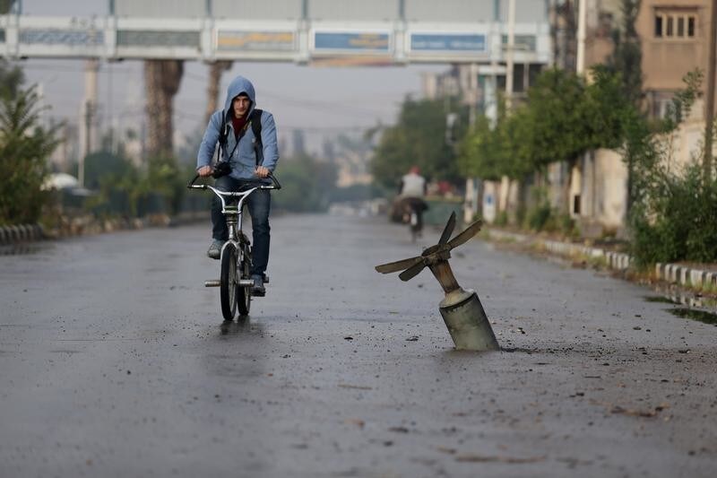 A resident rides his bicycle near what activists said was an exploded cluster bomb shell in the town of Douma, eastern Ghouta in Damascus November 5, 2015. REUTERS/Bassam Khabieh TPX IMAGES OF THE DAY - GF20000047196