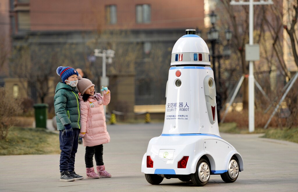 Children react next to a security robot patrolling inside a residential compound in Hohhot, Inner Mongolia, China January 18, 2019. REUTERS/Stringer ATTENTION EDITORS - THIS IMAGE WAS PROVIDED BY A THIRD PARTY. CHINA OUT. TPX IMAGES OF THE DAY - RC1FFD599740