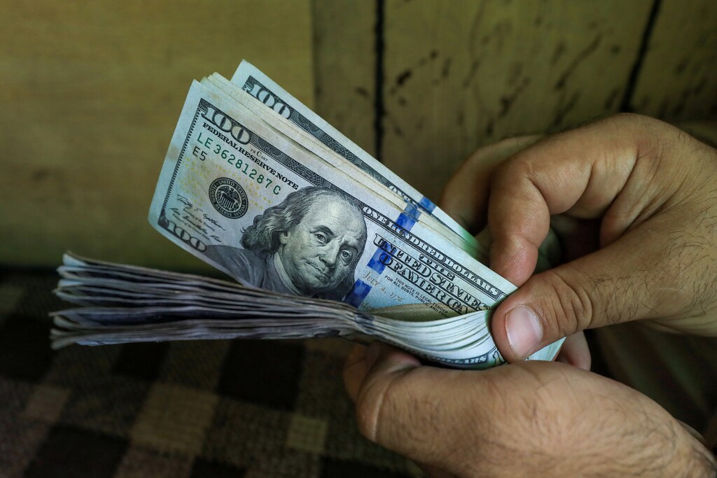 inflation: A trader counts U.S. dollar banknotes at a currency exchange booth in Peshawar, Pakistan