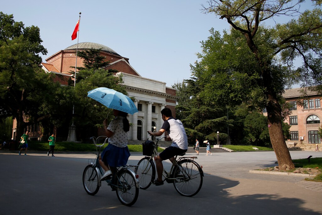 People cycle past the auditorium of Tsinghua University in Beijing, China, ranking 12th in the THE world university rankings