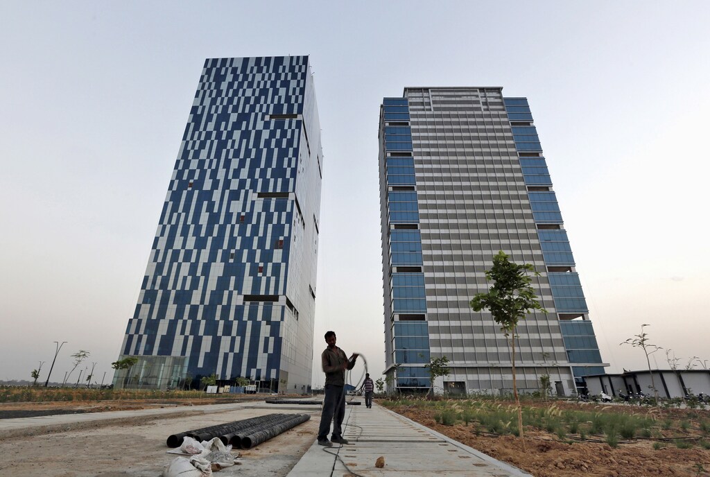 A worker folds the cable of a welding machine in front of two office buildings at the Gujarat International Finance Tec-City (GIFT) at Gandhinagar, in the western Indian state of Gujarat, April 10, 2015. India's push to accommodate a booming urban population and attract investment rests in large part with dozens of "smart" cities like the one being built on the dusty banks of the Sabarmati river in western India. Picture taken April 10, 2015. REUTERS/Amit Dave - GF10000057730