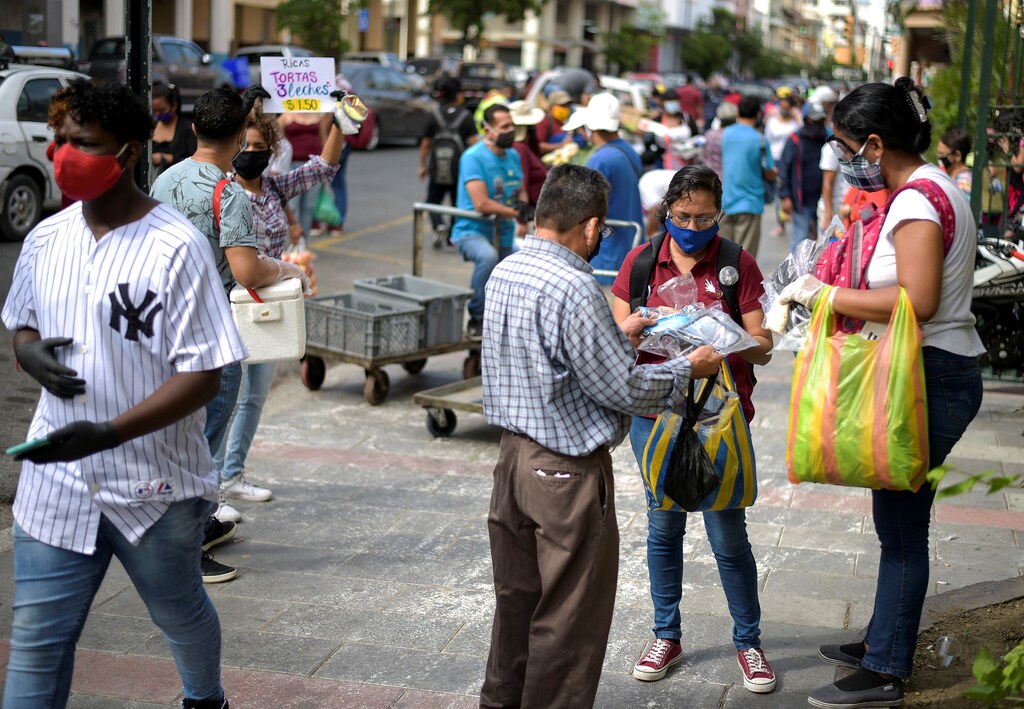 Los vendedores ambulantes ofrecen sus productos mientras otras personas caminan por la calle, ya que la ciudad permitió que algunos negocios reabrieran el miércoles después de una caída en las muertes diarias debido al brote de la enfermedad coronavirus (COVID-19), en Guayaquil, Ecuador, el 20 de mayo de 2020.
