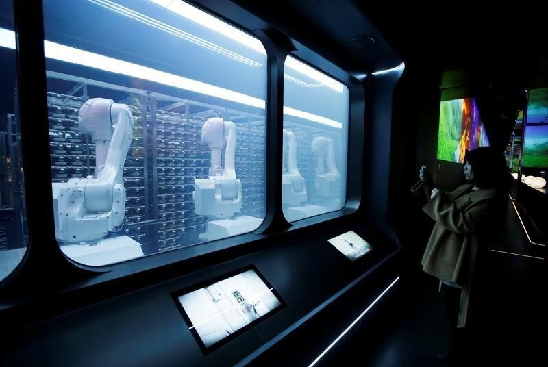 A customer takes a picture as robotic arms collect pre-packaged dishes from cold storage, done according to the diners' orders, at Haidilao's new artificial intelligence hotpot restaurant in Beijing, China, November 14, 2018. Picture taken November 14, 2018. REUTERS/Jason Lee - RC1BD5453A90