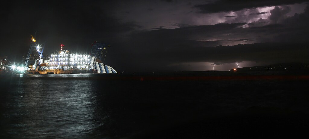 A lightning storm is pictured over the sea near the capsized cruise liner Costa Concordia lying surrounded by cranes outside Giglio harbour September 15, 2013. REUTERS/Tony Gentile (ITALY - Tags: DISASTER MARITIME ENVIRONMENT) - GM1E99G0I5501
