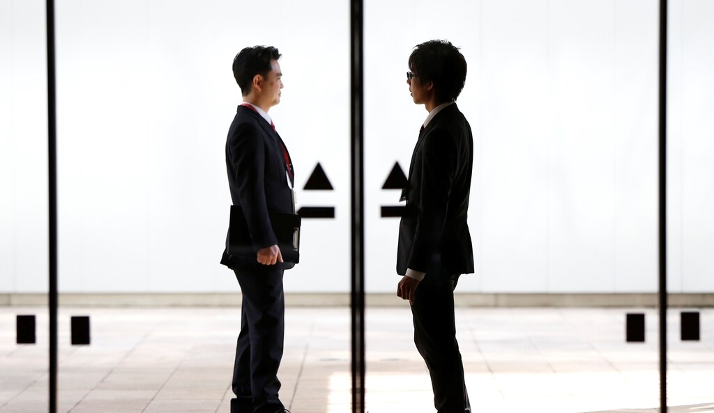 Men are seen through an automatic glass door in Tokyo, Japan April 6, 2017.