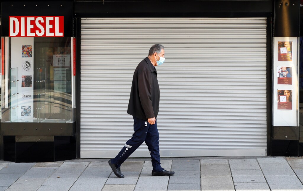 A man, wearing a protective face mask, walks past a closed shop after the Austrian government announced a lockdown including the closure of all non-essential shops, as the spread of the coronavirus disease (COVID-19) continues, in Vienna, Austria, November 17, 2020. REUTERS/Leonhard Foeger - RC2Z4K91CD8Z