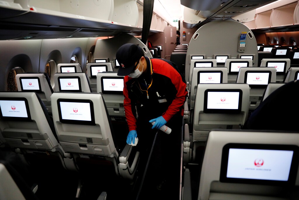 A staff member of Japan Airlines wearing a protective face mask and gloves cleans the cabin of a plane which performed a domestic flight, amid the coronavirus disease (COVID-19) outbreak at Haneda airport in Tokyo, Japan May 26, 2020. Picture taken May 26, 2020. REUTERS/Kim Kyung-Hoon - RC262H9ILONT
