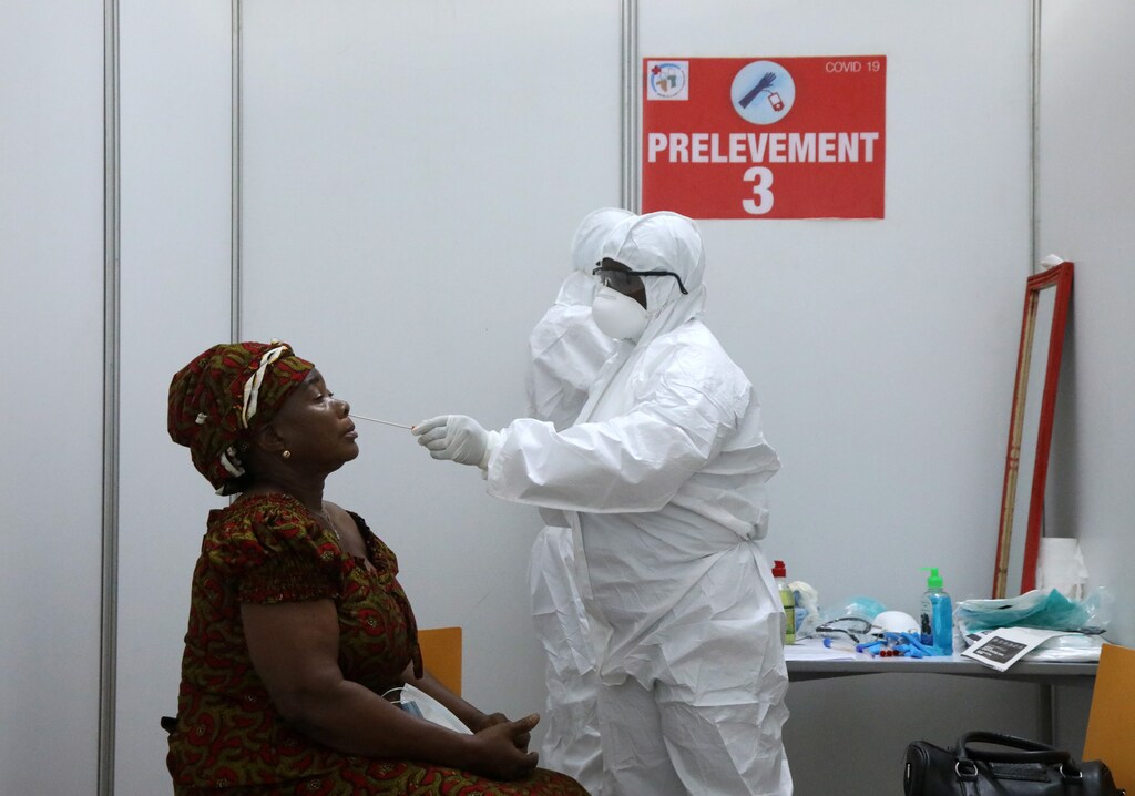 A member of medical staff wearing protective equipment takes a swab from a woman during screening tests, at the first reception center built to hold coronavirus disease screening tests, amid the spread of the coronavirus isease (COVID-19), in Abidjan, Ivory Coast April 15, 2020. REUTERS/Luc Gnago - RC295G9N7CEC