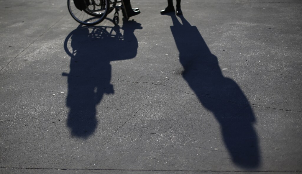 a shadow of a wheelchair user on the pavement