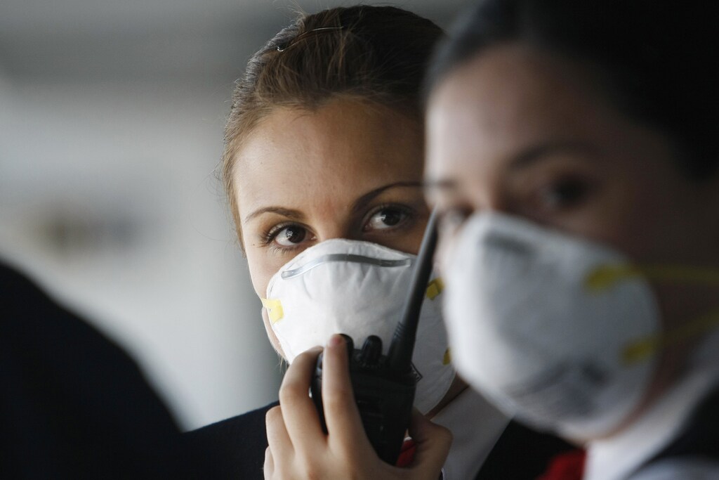 A worker wears a mask as she talks on a walkie-talkie at Santiago's international airport April 27, 2009. Governments around the world are rushing to reduce the impact of a possible swine flu pandemic due to a new virus that has killed 149 people in Mexico and spread to the U.S., Canada and Europe. REUTERS/Ivan Alvarado (CHILE TRANSPORT HEALTH) - GM1E54S06XJ01