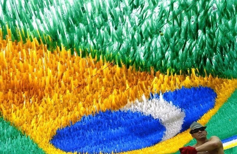 A man walks past coloured ribbons hanging over a street depicting the Brazilian national flag decorated for the 2014 World Cup in Manaus June 16, 2014. In a project called 'On the Sidelines' Reuters photographers share pictures showing their own quirky and creative view of the 2014 World Cup in Brazil. REUTERS/Yves Herman (BRAZIL - Tags: SPORT SOCCER WORLD CUP SOCIETY) - RTR3U4UE