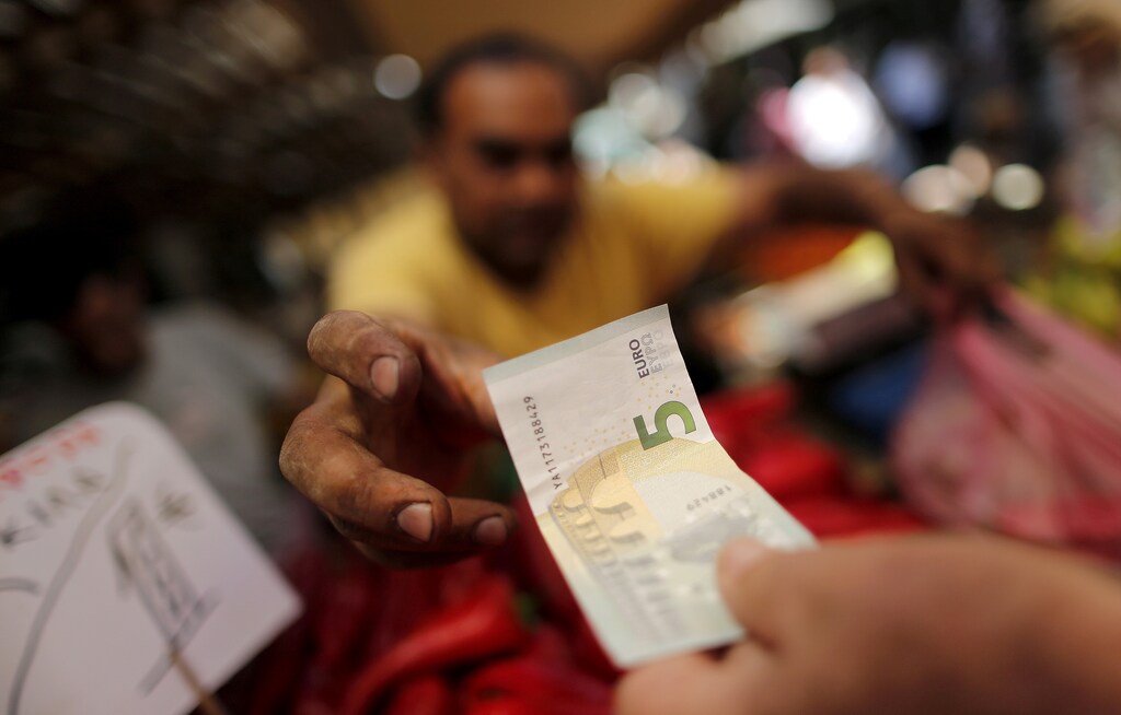 A vendor receives a five Euro bank note from a customer at the central market in Athens, Greece, July 8, 2015. REUTERS/Christian Hartmann/File Photo - D1BEUFAAEFAB