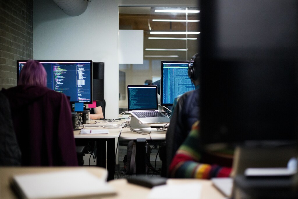 Employees in an office work on computers to strengthen cybersecurity.