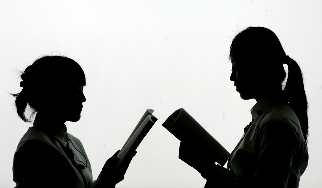 Two Korean women pose in the exhibition hall of Korea on the day of the opening of the Frankfurt book fair, October 18, 2005. The world's largest book fair with it's focal theme on Korean literature will be open to public from October 19 to 23. REUTERS/Alex Grimm - RP2DSFIITFAC