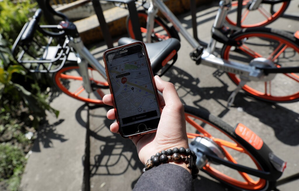 A smartphone shows the Mexican bike-sharing scheme Mobike app, near the scheme's shared bikes