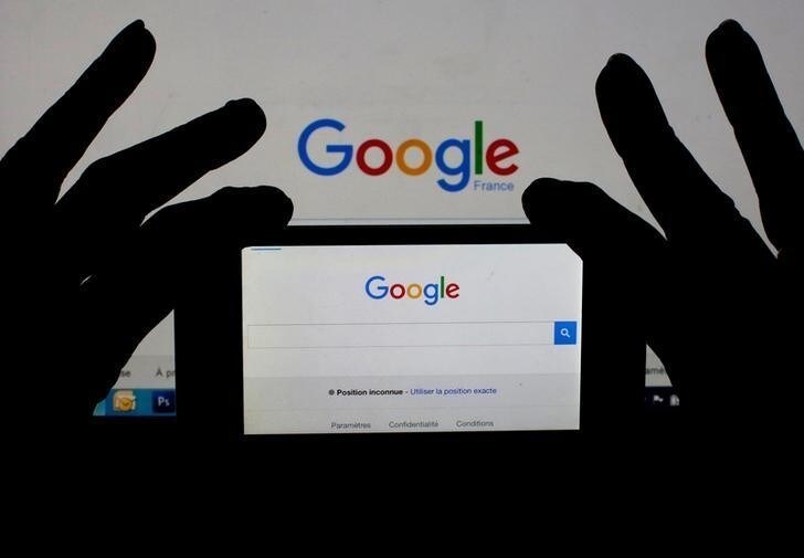 A woman holds her smart phone which displays the Google home page, in this picture illustration taken February 24, 2016. France is seeking 1.6 billion euros ($1.76 billion) in back taxes from U.S. Internet giant Google, criticised for its use of aggressive tax optimisation techniques, a source at the finance ministry said on Wednesday. REUTERS/Eric Gaillard/Illustration