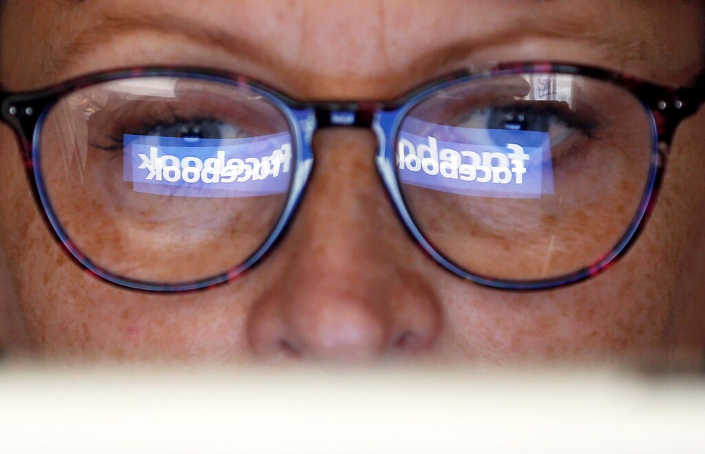 The Facebook logo is reflected on a woman's glasses in this photo illustration taken June 3, 2018. REUTERS/Regis Duvignau/Illustration - RC13DB520D70