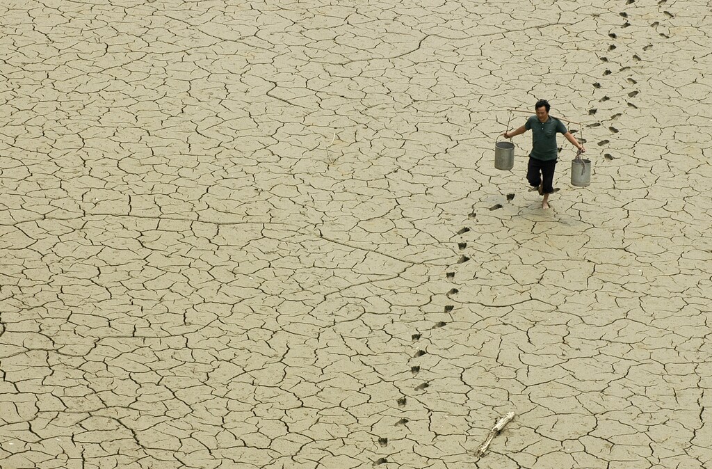 A farmer walks on a dried-up pond on the outskirts of Baokang, central China's Hubei province, June 10, 2007. REUTERS/Stringer (CHINA) CHINA OUT - GM1DVLKPZKAA