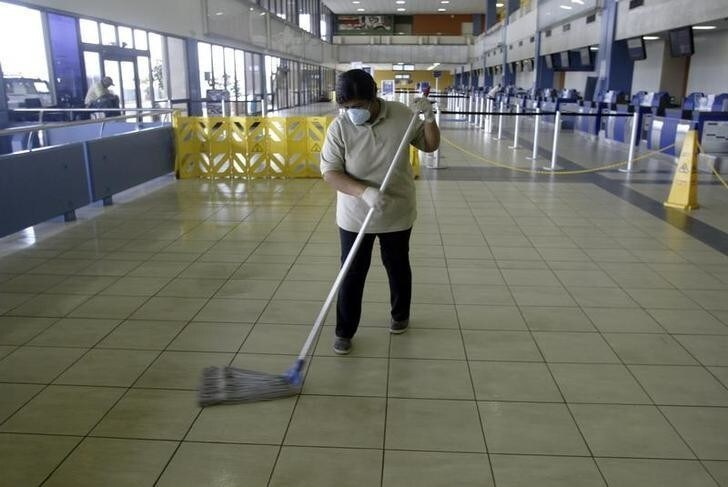 An airport cleaning lady mops the floor while protecting herself with a surgical mask against the swine flu in Panama City April 27, 2009. Panama's health department is on alert at the Tocumen international airport against the swine flu. REUTERS/Alberto Lowe (PANAMA HEALTH TRANSPORT)