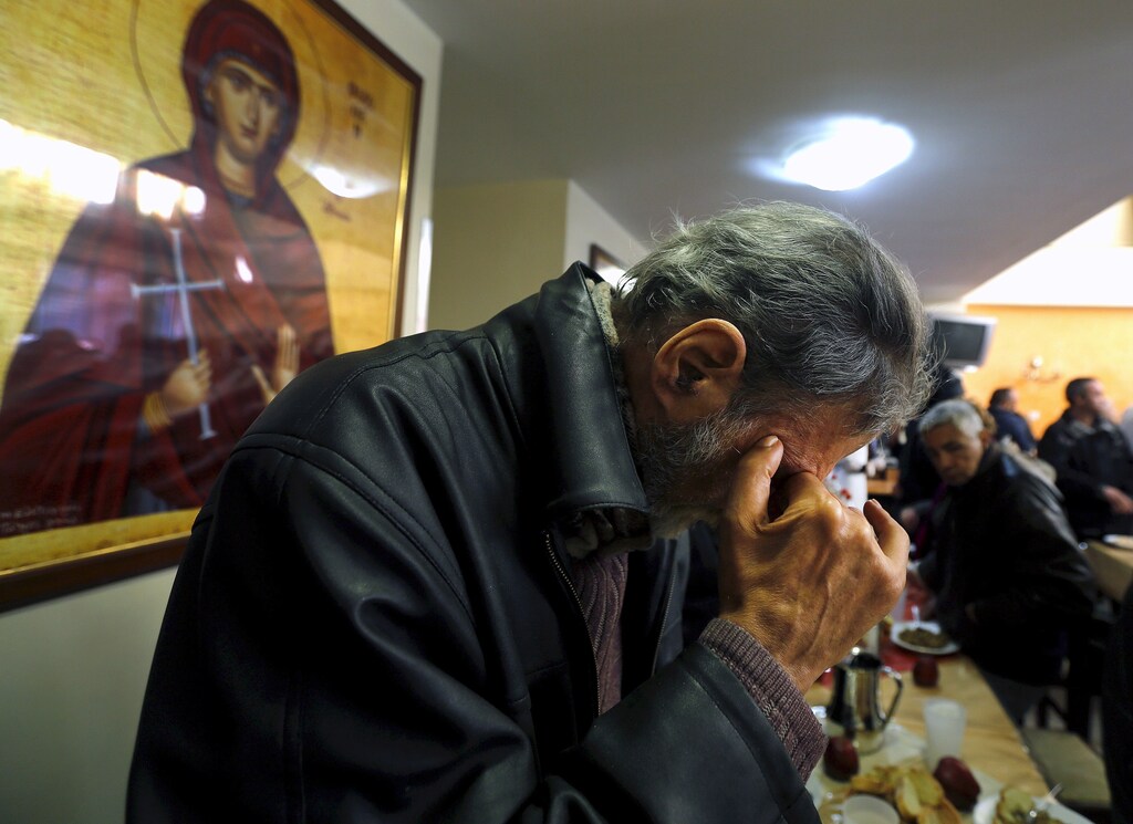 A man prays before his lunch at the Orthodox church "Galini" foundation soup kitchen in Athens, Greece in this March 19, 2015 file photo. To match Special Report EUROZONE-GREECE/NEGOTIATIONS REUTERS/Yannis Behrakis/Files - GF10000139587