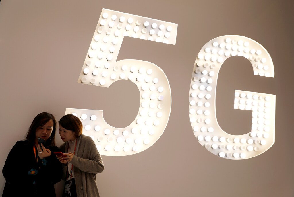 Visitors use their mobiles phones as they stand next to a 5G Led Smart Bulb panel inside the Xiaomi booth at the Mobile World Congress in Barcelona, Spain, February 26, 2019. REUTERS/Rafael Marchante - RC199EF0A890