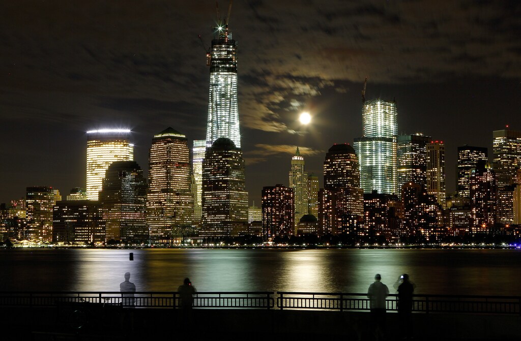 The moon rises behind the skyline of New York's Lower Manhattan and One World Trade Center as people stand along the Hudson River in Jersey City, New Jersey, October 1, 2012. Picture taken with a 30 second exposure. REUTERS/Gary Hershorn (UNITED STATES - Tags: CITYSPACE TPX IMAGES OF THE DAY) - GM1E8A20P6C01