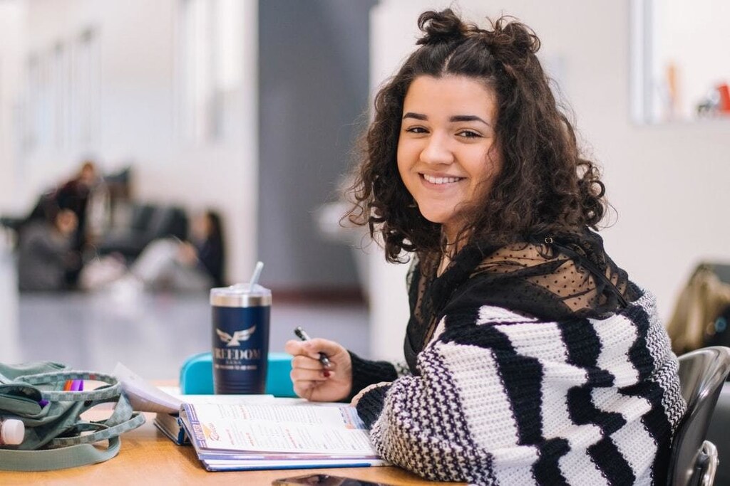 Girl sits at desk doing work at university.
