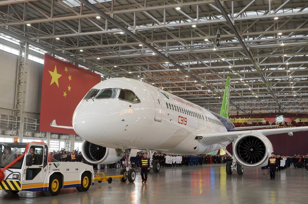 The first C919 passenger jet made by the Commercial Aircraft Corp of China (Comac) is pulled out during a news conference next to a Chinese national flag at the company's factory in Shanghai, November 2, 2015. Comac rolled out China's first homemade 158-seated C919 narrow body jet, which is meant to rival similar models from Airbus Group and Boeing Co. State television also showed footage of the aircraft rolling off the assembly line in Comac's Shanghai factory. In a statement, the company said it had already received 517 orders for the aircraft mainly from domestic firms. REUTERS/China Daily CHINA OUT. NO COMMERCIAL OR EDITORIAL SALES IN CHINA - RTX1UBTB