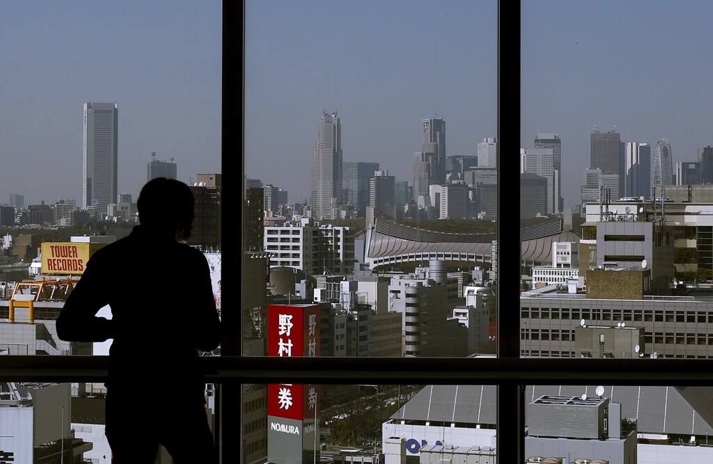 A man is silhouetted against a window overlooking central Tokyo, Japan, March 17, 2016. REUTERS/Thomas Peter - RTSATRB