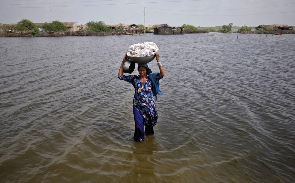 A woman carries her belongings as she wades through flood waters in the Badin district of Pakistan's Sindh province September 19, 2011. The latest floods, triggered by monsoon rains, have killed more than 230 people, destroyed or damaged 1.2 million houses and flooded 4.5 million acres (1.8 million hectares) since late last month, officials and Western aid groups say. More than 300,000 people have been moved to shelters. Some 800,000 families hit by last year's floods are still homeless. Aid groups have warned of a growing risk of fatal diseases. REUTERS/Akhtar Soomro (PAKISTAN - Tags: DISASTER ENVIRONMENT HEALTH TPX IMAGES OF THE DAY)