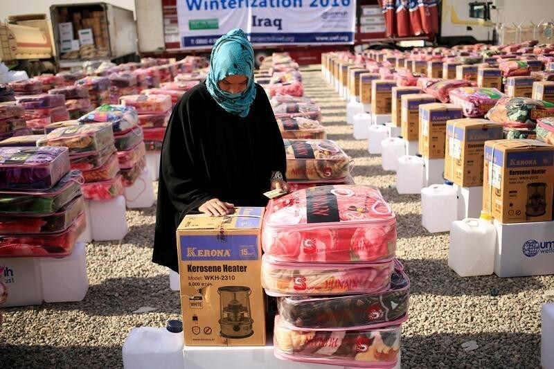 A newly internally displaced woman stands beside her humanitarian aid supplies at Al Khazer camp, east of Mosul, Iraq, November 14 2016. REUTERS/Zohra Bensemra - RTX2TKUX