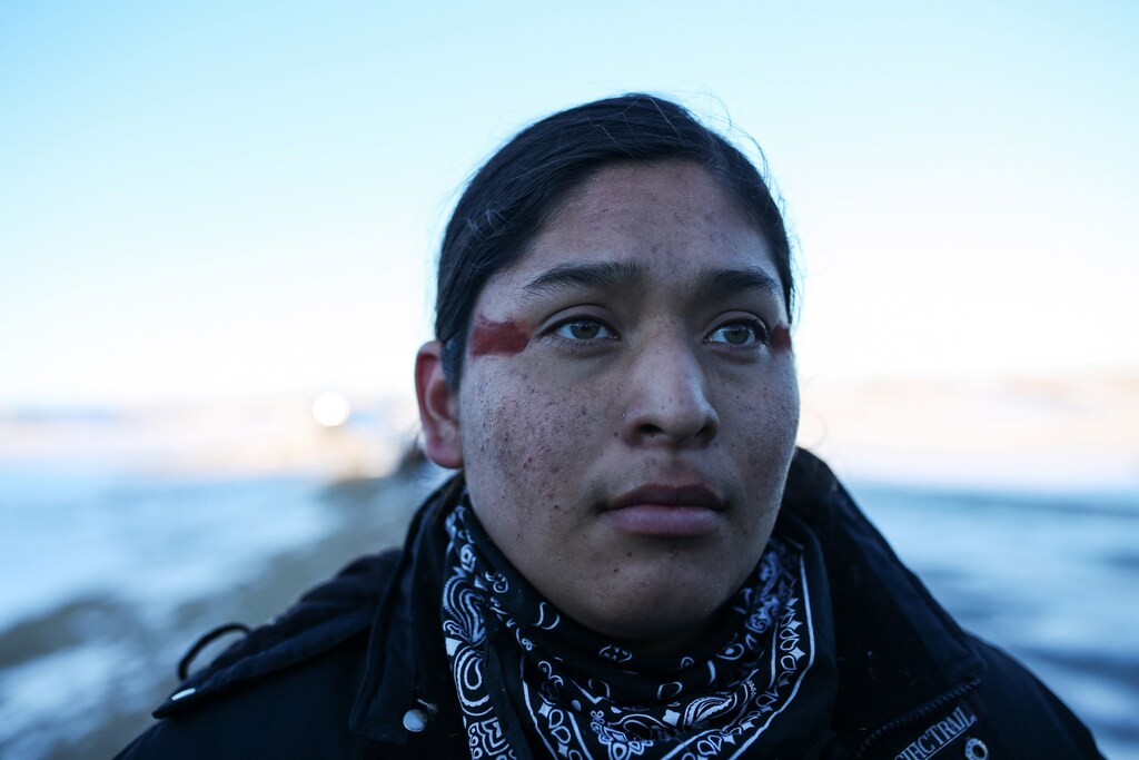 Activist Nicholas Cortez, 18, of Pyramid Lake Paiute Tribe, helps block people from traveling on Route 1806 to a police barricade north of Oceti Sakowin camp where "water protectors" continue to demonstrate against plans to pass the Dakota Access pipeline adjacent to the Standing Rock Indian Reservation, near Cannon Ball, North Dakota, U.S., December 4, 2016. Picture taken December 4, 2016. REUTERS/Stephen Yang - RC148D6C46A0