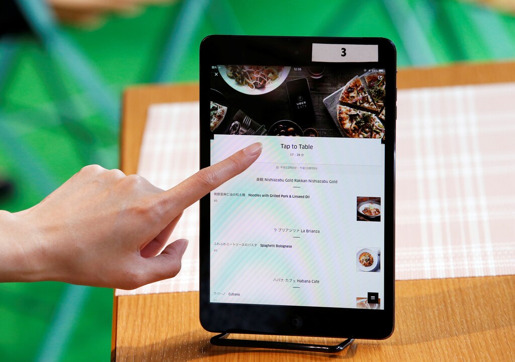 A woman tries UberEats' application on a tablet at the launching event of food-delivery service UberEats in Tokyo, Japan, September 28, 2016. REUTERS/Kim Kyung-Hoon - RTSPS1R