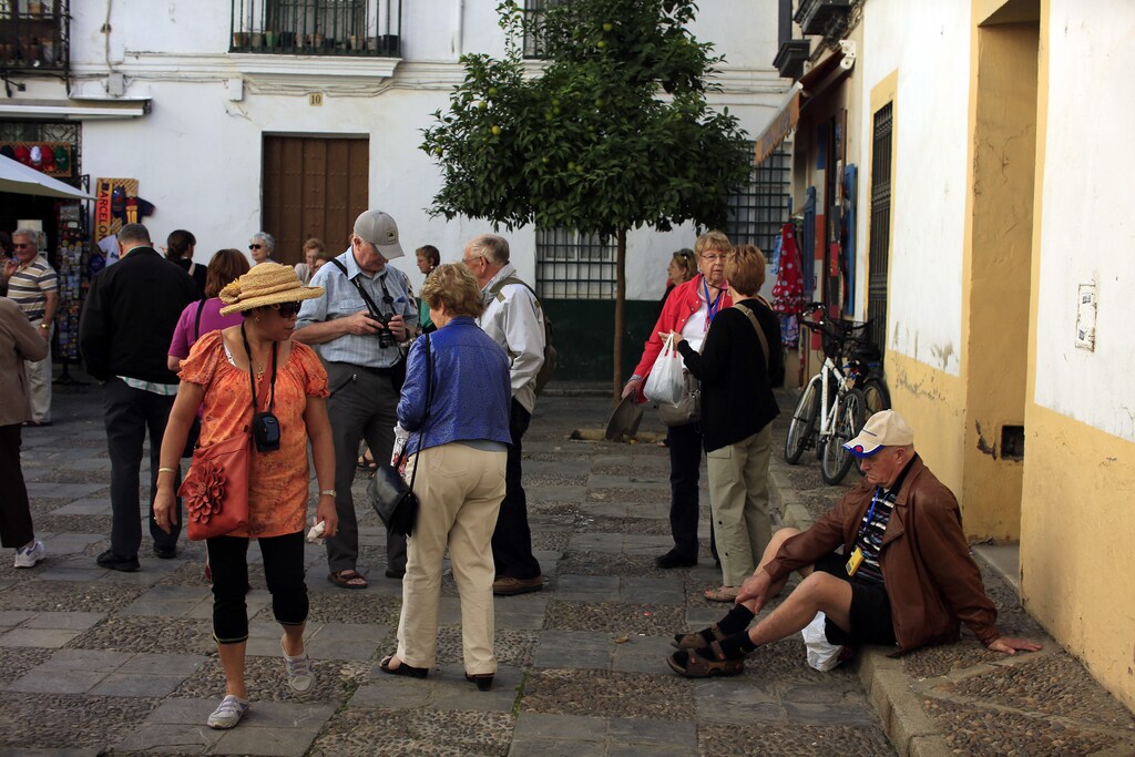 A tourist sits on the pavement next to companions as he takes a rest in the Andalusian capital of Seville, southern Spain October 30, 2013. Spain just pulled clear of recession in the third quarter and inflation eased in October, data showed, laying foundations for a gradual recovery in consumer spending though the country's economic crisis looks far from over. Gross domestic product (GDP) inched 0.1 percent higher between July and September, state statistics agency INE said, notching up the first quarter-on-quarter growth since the beginning of 2011 and officially ending a two-year slump. REUTERS/Marcelo del Pozo (SPAIN - Tags: BUSINESS TRAVEL) - GM1E9AV09QI01