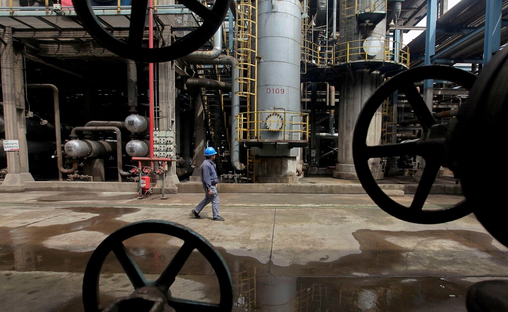A worker walks past oil pipes at a refinery in Wuhan, Hubei province March 23, 2012. REUTERS/Stringer/File Photo - RTSLRAT