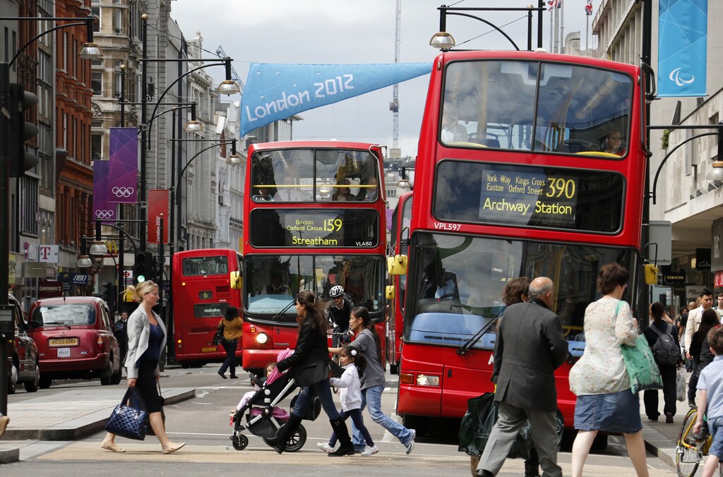 Double decker buses drive past posters of Olympic Rings and flags advertising the London 2012 Olympics at Oxford Street in London July 13, 2012. The London 2012 Olympics run from July 27 to August 12. REUTERS/Fabrizio Bensch (BRITAIN - Tags: SPORT OLYMPICS TRANSPORT) - GM1E87D1QRW01