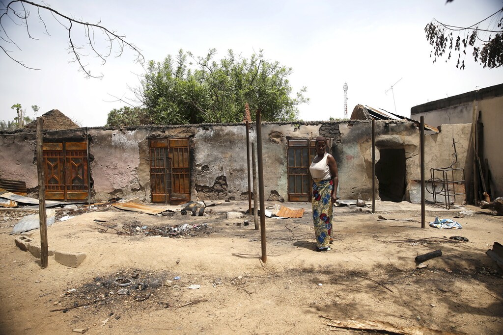 A woman stands in front of a burnt building in Michika town, after the Nigerian military recaptured it from Boko Haram, in Adamawa state May 10, 2015.