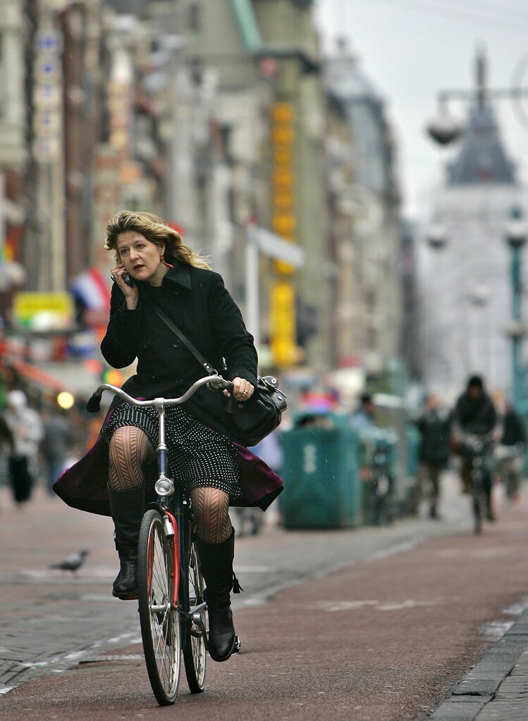 A women talks on her mobile phone while riding a bike in Amsterdam January 17, 2007. REUTERS/Koen van Weel (NETHERLANDS)