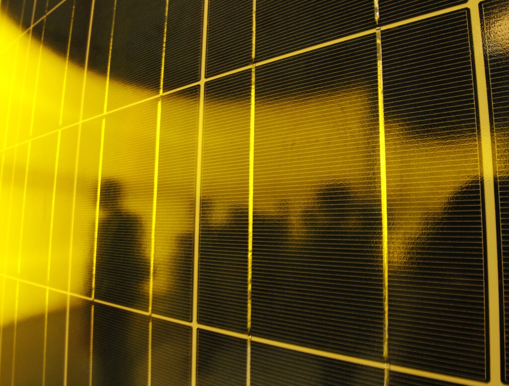 People are silhouetted on a solar panel display by solar module supplier Upsolar at the fourth International Photovoltaic Power Generation (PV) Expo in Tokyo