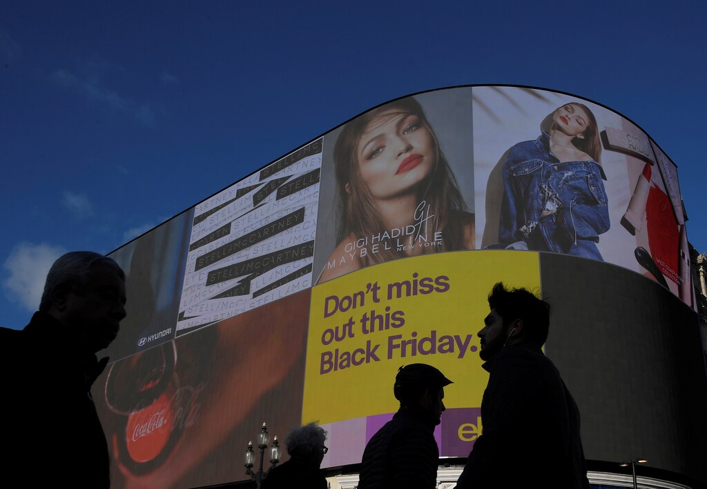 Shoppers are seen walking past the electronic billboard at Piccadilly Circus, showing retail adverts incuding one for 'Black Friday' in London, Britain, November 23, 2017. REUTERS/Toby Melville - RC14BDFDA300
