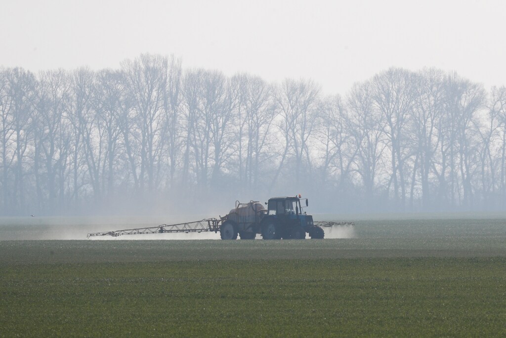 A tractor spreading fertilizers on a field.