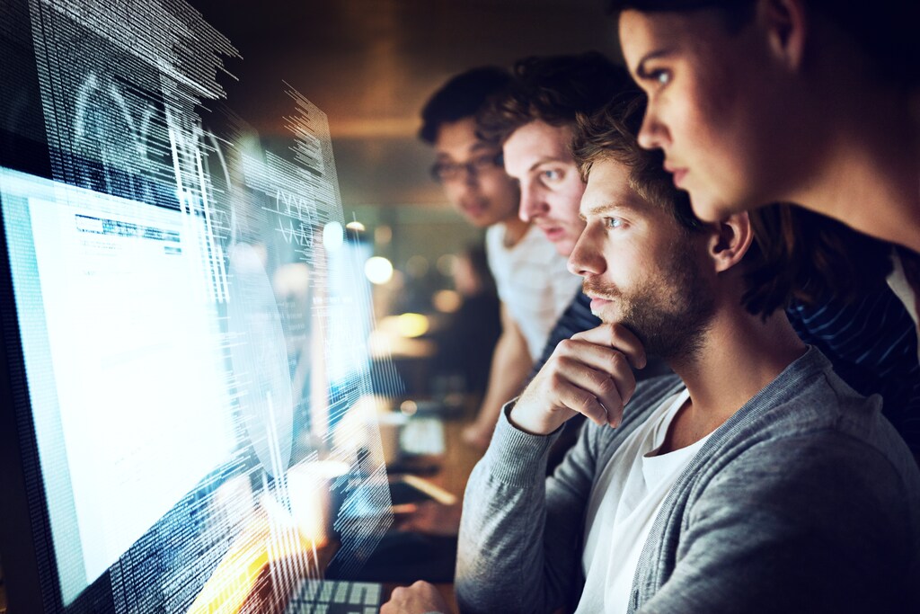 Fotografía de un grupo de programadores trabajando en un código de computadora por la noche; computación cuántica