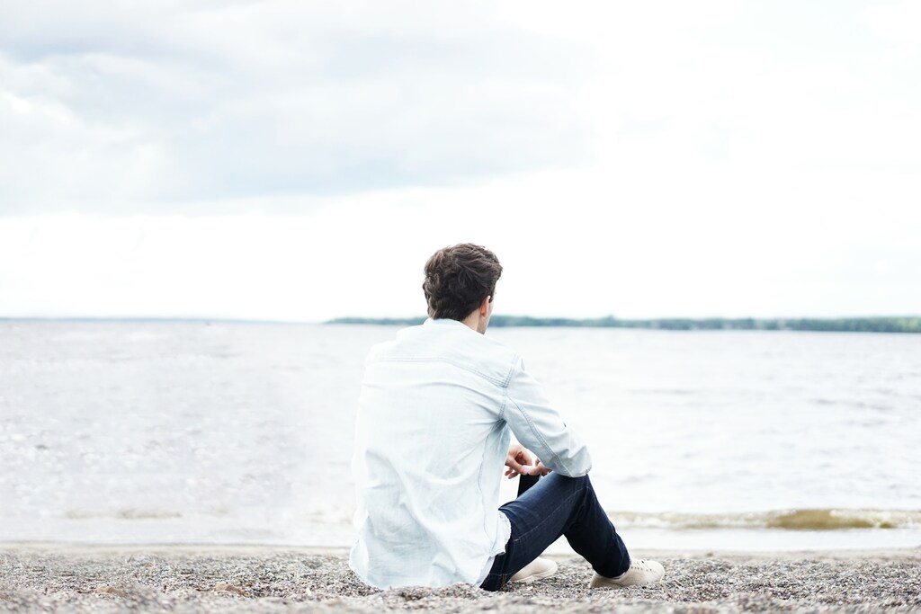 A man thinking on a beach, illustrating the mental health crisis